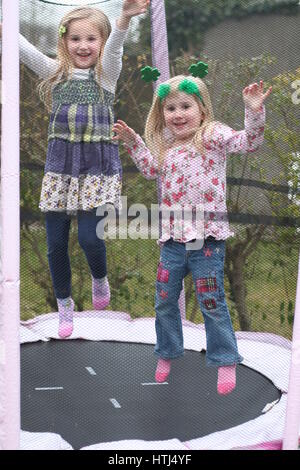 Heureux plaisir blondes, les enfants, les enfants jouant à très heureux de rire et sourire de sauter sur un trampoline dans le jardin Banque D'Images