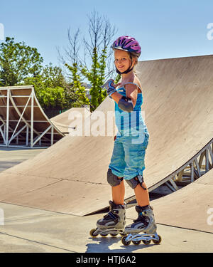 Girl casque roller skate parc à pied. Équitation enfant sur patins à roulettes. Banque D'Images