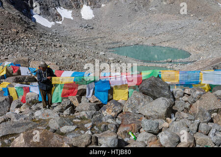 L'homme bouddhiste tibétain, nouer le pèlerin Lung ta les drapeaux de prières à Dolma La pass en route Mt. Kailash Kora Banque D'Images