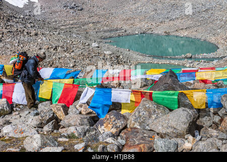 L'homme bouddhiste tibétain, nouer le pèlerin Lung ta les drapeaux de prières à Dolma La pass en route Mt. Kailash Kora Banque D'Images