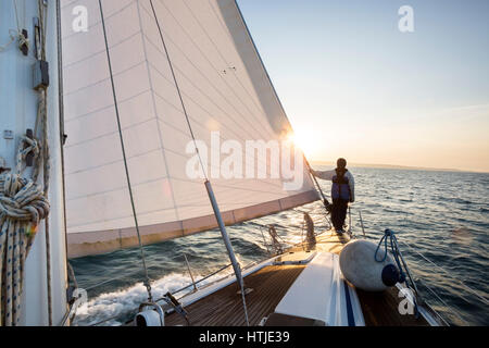 Homme debout sur l'avant de la voile en mer Banque D'Images