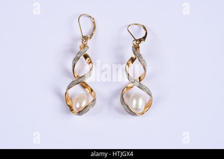 L'or et diamant boucles d'torsadée avec un grand pearl à l'intérieur sur un fond blanc, au Royaume-Uni. Banque D'Images