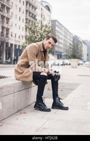 Beau jeune homme aux cheveux courts posant dans un contexte urbain. Banque D'Images