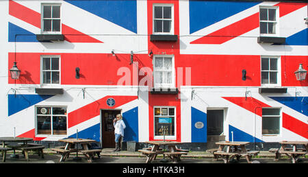 Femme debout prenant un verre devant un pub peint avec un jack d'Union - le syndicat inn à Saltash, Cornwall. Pris pendant le brexit Banque D'Images