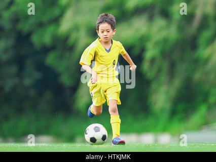 Enfant jouant au football japonais Banque D'Images