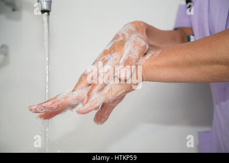 Se laver les mains avec de l'eau savonneuse en milieu clinique Banque D'Images