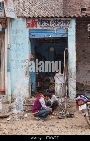 Un mécanicien non identifiés la réparation à un cycle de moteur en bordure de village, atelier de réparations à l'état indien du nord de l'Uttar Pradesh Banque D'Images