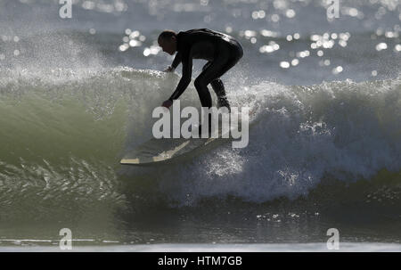 Manèges d'un surfer une vague sur la plage de Boscombe Bournemouth, Dorset, qu'aujourd'hui pourrait être l'un des jours les plus chauds de l'année jusqu'à présent avec un peu plus de ressort dans une semaine. Banque D'Images