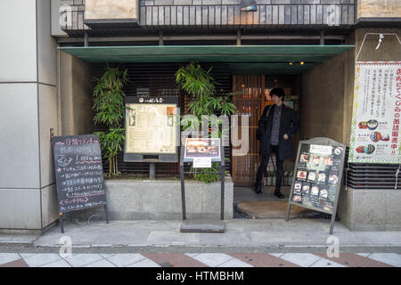 Un homme en sortant d'un restaurant qui sert de la viande de baleine, à Shibuya Tokyo Japon. Banque D'Images