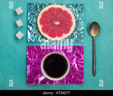 Tranche d'Orange et une tasse de café sur les stands fait en or jaune et turquoise aluminium sur une surface en bois Banque D'Images