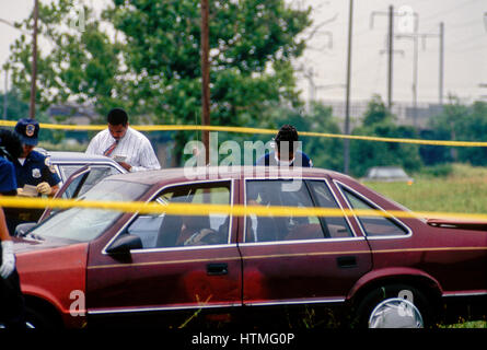 Le bureau de détectives de l'homicide de la police de district de Columbia ainsi que des techniciens de scène de crime un crime de meurtre processus sene où la victime qui avait été abattu était toujours allongée sur le siège arrière de la voiture. Les voisins musicaux et d'éventuels témoins se tiennent autour de l'extérieur de la scène du crime jaune pour regarder les bandes venues sur Washington DC., 1996.Photo par Mark Reinstein Banque D'Images