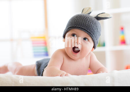 Smiling cute baby enfant en costume de lapin lying on bed in nursery Banque D'Images