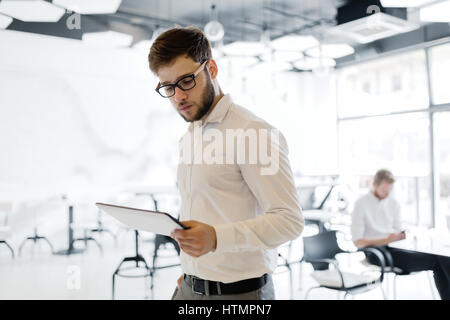 Confident businessman wearing shirt et lunettes à l'aide de tablet Banque D'Images