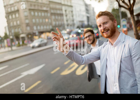 Businessman waving pour un taxi en ville animée Banque D'Images