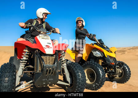 Quad conduisant des personnes - happy smiling couple bikers en désert de sable. Banque D'Images