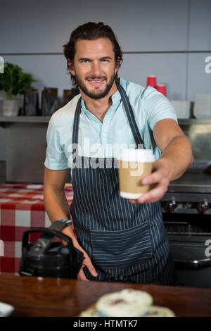 Portrait de personnel masculin holding dessert on cake stand at counter in coffee shop Banque D'Images