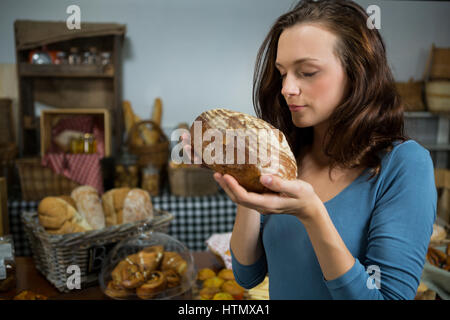 Woman smelling pain à comptoir de boulangerie dans le marché Banque D'Images