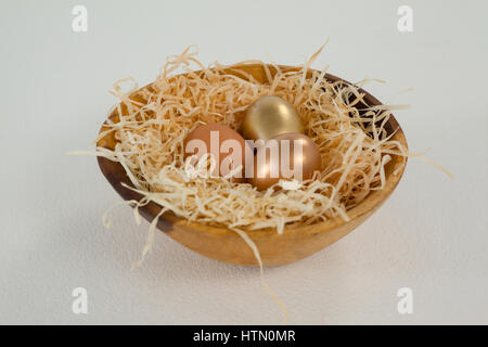Les oeufs de Pâques dans un bol d'or against white background Banque D'Images