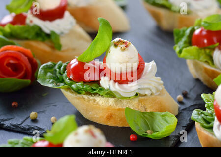 De délicieuses entrées froides : tranches de baguette avec cerise Tomate, mozzarella, fromage à la crème, l'huile d'olive et de feuilles de basilic Banque D'Images