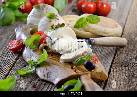 Fromage mozzarella italienne snack avec tomates cerises, le basilic et les olives servi sur une planche en bois avec du pain toast Banque D'Images