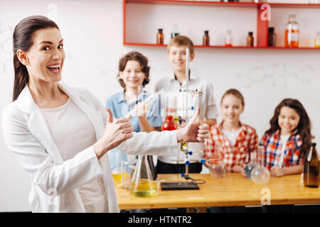 Bon travail. Heureux heureux teacher standing positive dans la classe et showing Thumbs up sign tout en étant fier de ses élèves Banque D'Images
