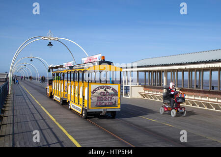 Southport, Merseyside, Royaume-Uni. Météo britannique. 14 mars, 2017. Senior, retraité personne handicapée à l'aide de mobility scooter sur un lumineux, aéré avec ciel bleu pour pier les poussettes. Barmy Mars les températures continuent dans le nord ouest, mais avec un peu plus de vent que de la fin. Les gens sont bien couvert contre la brise de mer comme ils le pied à la fin de la 2e plus longue jetée en Angleterre. Credit : MediaWorldImages/Alamy Live News Banque D'Images