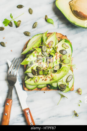 Petit-déjeuner veggie vert sain concept. Sandwich à l'avocat, concombre, chou frisé, chou de kress, graines de citrouille sur en arrière-plan, Vue de dessus. Vegan, w Banque D'Images