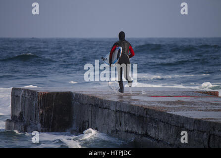 Surfer s'exécute dans l'eau de porter une combinaison isothermique en hiver. Cold wind surf. Splash vague combinaison imperméable. Banque D'Images