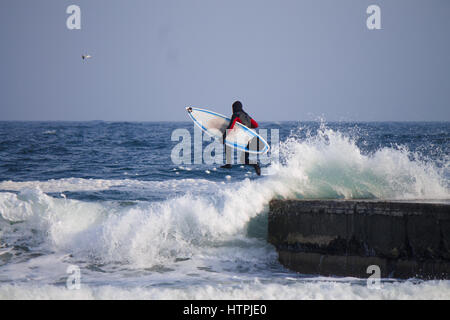 Surfer de sauter dans l'eau de porter une combinaison isothermique en hiver. Cold wind surf. Splash vague combinaison imperméable. Banque D'Images