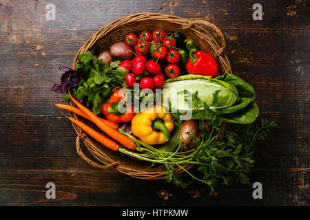 Des légumes frais dans le panier sur fond de bois Banque D'Images