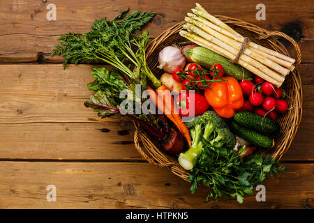 Des légumes frais dans le panier sur fond de bois Banque D'Images