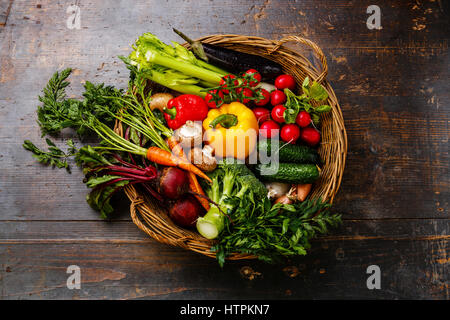 Des légumes frais dans le panier sur fond de bois Banque D'Images