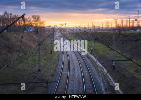 Belle vue depuis le pont sur le chemin de fer au coucher du soleil. Paysage industriel colorés avec gare, ciel nuageux bleu et jaune du soleil. Rai Banque D'Images