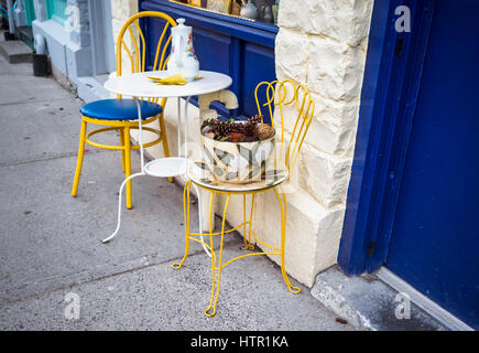 Cafe patio montrant deux chaises avec un verre d'eau sur une belle journée. Le café bleu portes contre les murs jaune ajoute encore à une dynamique scène de charme Banque D'Images