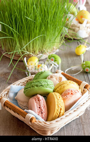 Macarons meringues multicolores dans un panier en osier d'oeufs de Pâques Banque D'Images