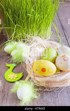 Les oeufs de pâques de diverses couleurs allongé sur la table à côté de l'herbe fraîche Banque D'Images