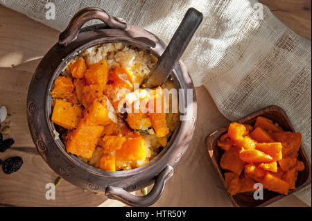 Bouillie de blé végétariens avec de gros morceaux de citrouille rôties dans un pot en argile dans un style rustique de l'alimentation biologique Banque D'Images