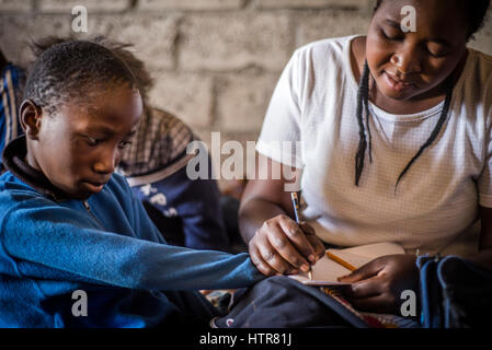 Bénévole de l'accueil de bonheur aide un garçon à faire une tâche pendant une leçon à Lusaka, Zambie. La maison du Bonheur est un orphelinat centre fondé en 2015 par Bernadetta Mindeo. Il y a 62 enfants dans le centre, 25 d'entre eux vivent dans la maison du bonheur en permanence. Vingt bénévoles prennent soin des garçons et des filles ayant différents types de handicaps. La maison du bonheur est situé dans deux pièces immeuble sans installations. Les bénévoles préparent les aliments sur le feu, lavez les vêtements pour enfants à l'extérieur. Banque D'Images