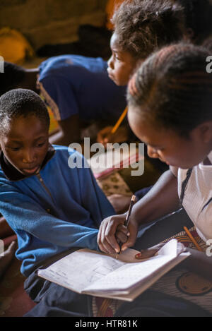 Bénévole de l'accueil de bonheur aide un garçon à faire une tâche pendant une leçon à Lusaka, Zambie. La maison du Bonheur est un orphelinat centre fondé en 2015 par Bernadetta Mindeo. Il y a 62 enfants dans le centre, 25 d'entre eux vivent dans la maison du bonheur en permanence. Vingt bénévoles prennent soin des garçons et des filles ayant différents types de handicaps. La maison du bonheur est situé dans deux pièces immeuble sans installations. Les bénévoles préparent les aliments sur le feu, lavez les vêtements pour enfants à l'extérieur. Banque D'Images