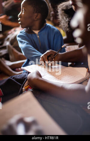 Bénévole de l'accueil de bonheur aide un garçon à faire une tâche pendant une leçon à Lusaka, Zambie. La maison du Bonheur est un orphelinat centre fondé en 2015 par Bernadetta Mindeo. Il y a 62 enfants dans le centre, 25 d'entre eux vivent dans la maison du bonheur en permanence. Vingt bénévoles prennent soin des garçons et des filles ayant différents types de handicaps. La maison du bonheur est situé dans deux pièces immeuble sans installations. Les bénévoles préparent les aliments sur le feu, lavez les vêtements pour enfants à l'extérieur. Banque D'Images