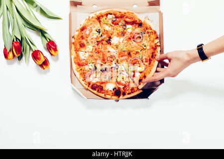 La main de femme prend un morceau de pizza de la boîte, vue d'en haut Banque D'Images
