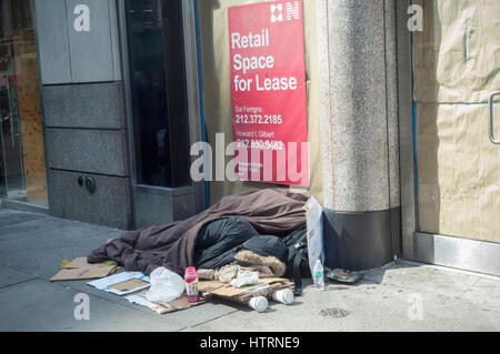 Une personne sans-abri dort en face d'une devanture vacants à New York le samedi 11 mars, 2017. (© Richard B. Levine) Banque D'Images