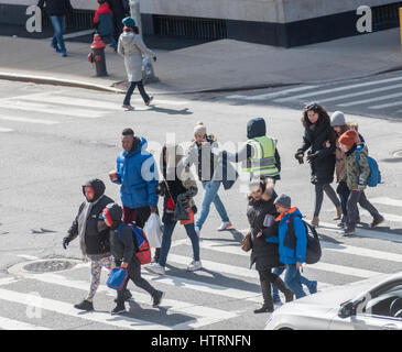 Les étudiants et leurs tuteurs sous l'œil attentif d'un cross crossing guard 9e Avenue en face de PS 33 à Chelsea à New York Lundi, Mars 13, 2017. En raison de la tempête approchant le maire Bill De Blasio a commandé les écoles pour être fermé le mardi, ainsi qu'un côté de la rue, parking étant suspendu. (© Richard B. Levine) Banque D'Images