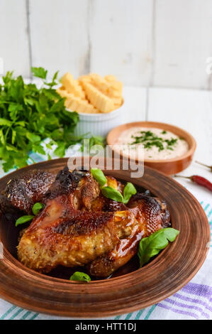 Ailes frit (canard, poulet) dans un glaçage au miel dans une cuvette d'argile sur un fond clair. Banque D'Images