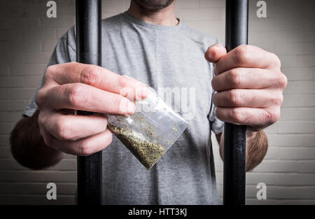 Un prisonnier derrière les barreaux de prison holding drogues ou psychotropes légales Spice (photo posée par modèle pour illustrer le problème des drogues dans les prisons du Royaume-Uni) Banque D'Images