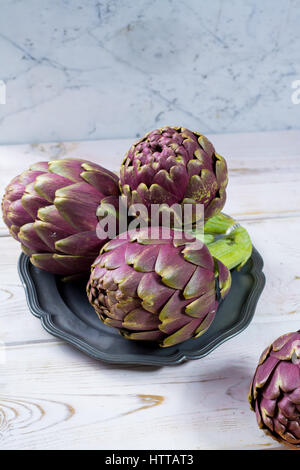 Grand frais artichauts Romanesco violet-vert prêt à cuire les fleurs de saison Banque D'Images