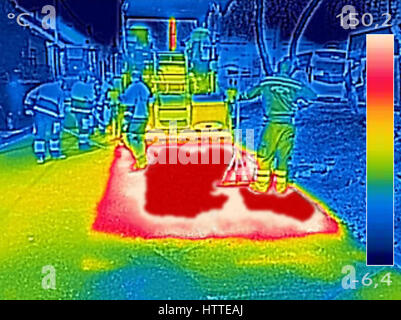 Thermovision infrarouge image montrant les travailleurs sur l'asphaltage de la machine à paver la route pendant la réparation de la rue fonctionne Banque D'Images