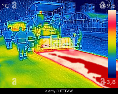 Thermovision infrarouge image montrant les travailleurs sur l'asphaltage de la machine à paver la route pendant la réparation de la rue fonctionne Banque D'Images