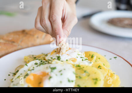 Femme part avec morceau de pain frit trempant dans de l'œuf œuf d'une cuisine typiquement espagnole, avec des tranches de pommes de terre sautées, et le persil haché Banque D'Images