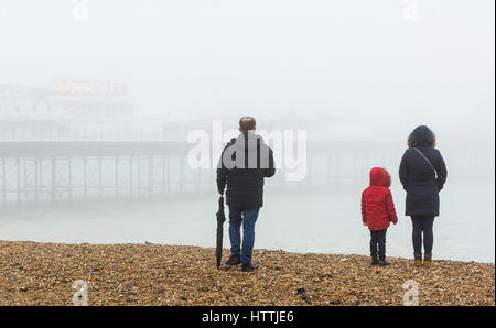 Famille sur une plage au bord de la mer en un jour brumeux à Brighton, East Sussex, Angleterre, Royaume-Uni. Banque D'Images